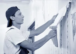 Ein Tapezierer tapeziert eine Wand.