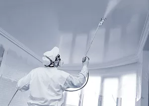 Ein Maler mit Kenntnissen in Airless-Technik arbeitet mit einem Sprühsystem.