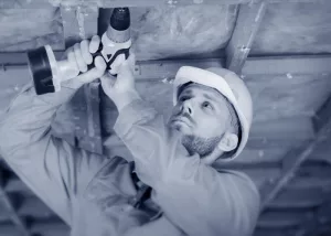 Ein Bauhelfer bei der Arbeit mit einem Akkuschrauber.