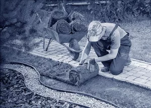 Ein Landschaftsbauer rollt Rasen in einem Garten aus.