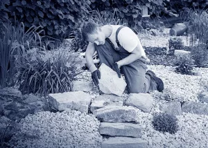 Ein Landschaftsbauer in einem Garten am Verlegen von Steinen.