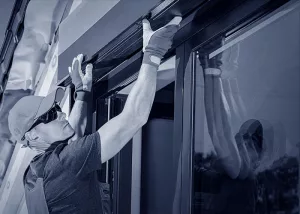 Ein Sonnenschutzmonteur bringt einen Sonnenschutz oben am Fenster an.