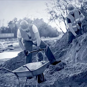 Zwei Bauhelfer beim Arbeiten auf einer Baustelle.
