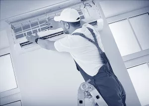 Ein Lüftungsmonteur installiert eine Raum-Klimaanlage.